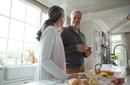 Instantánea de una pareja conversando junto a la encimera de su cocina.