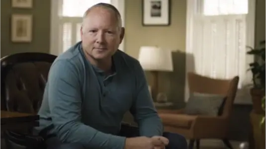 A man wearing a blue shirt sits and faces the camera. Text on the bottom right of the image reads "Jimmy's Story"